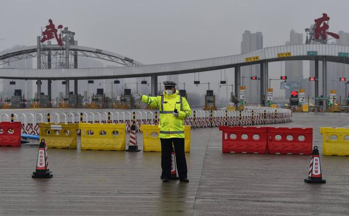 1月25日,一名警察在警方封锁的一条高速公路前,示意人们不准离开武汉市。(HECTOR RETAMAL/AFP via Getty Images)