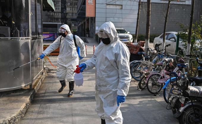 图为穿着防护服的工作人员为湖北省武汉市的一个地区进行消毒防疫工作。(图片来源:HECTOR RETAMAL/AFP via Getty Images)