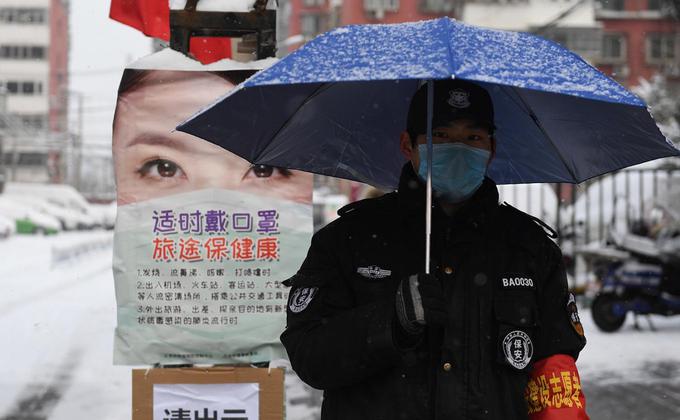 在大陆仍未防疫成功之际,中共官方却忙着出版《大国战疫》书籍,引起许多大陆民众的强烈反感。图2020年2月6日的一个雪天,一名保安在北京某住宅区的入口处打着伞执勤。(图片来源:GREG BAKER/AFP via Getty Images)