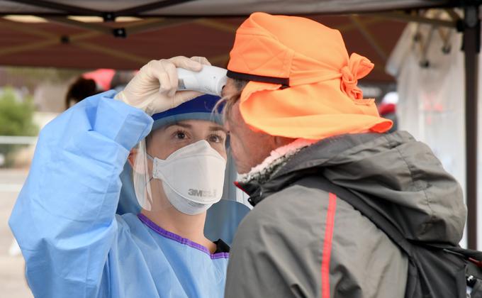 图为美国防疫人员用测温枪为一名无家可归者测量体温。(图片来源:Ethan Miller/Getty Images)